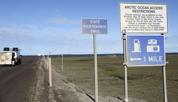 State Maintenance Ends sign at north end of AK 11, with other signs pointing to traveler services and Arctic Ocean access rules