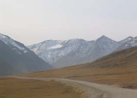 Unpaved highway, on elevated gravel roadbed, approaching Atigun Pass from the north